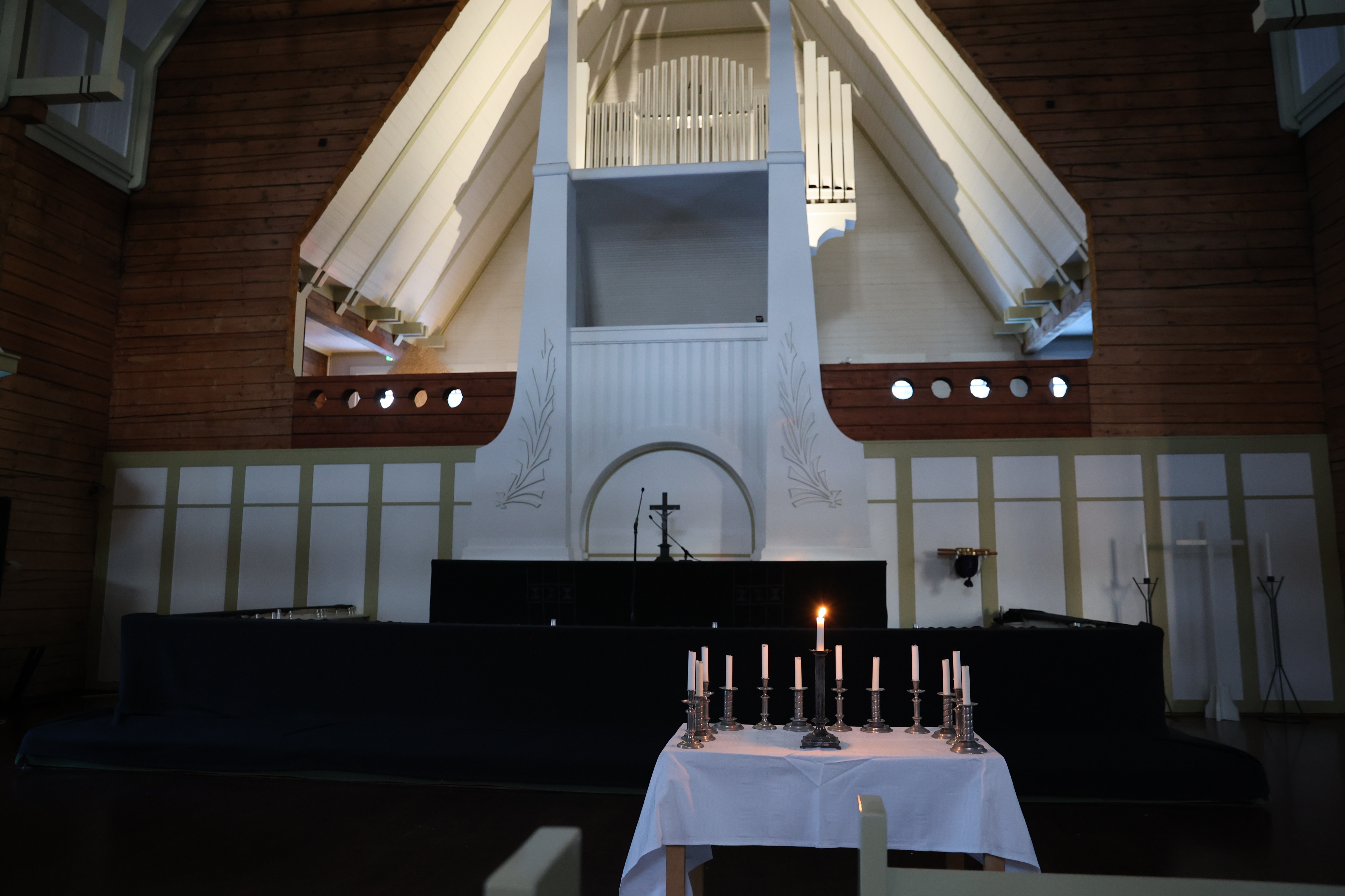Oulujoen kirkon alttari, joka on peitetty mustalla kankaalla. Valot on sammutettu. Alttarin edessä on pöytä...