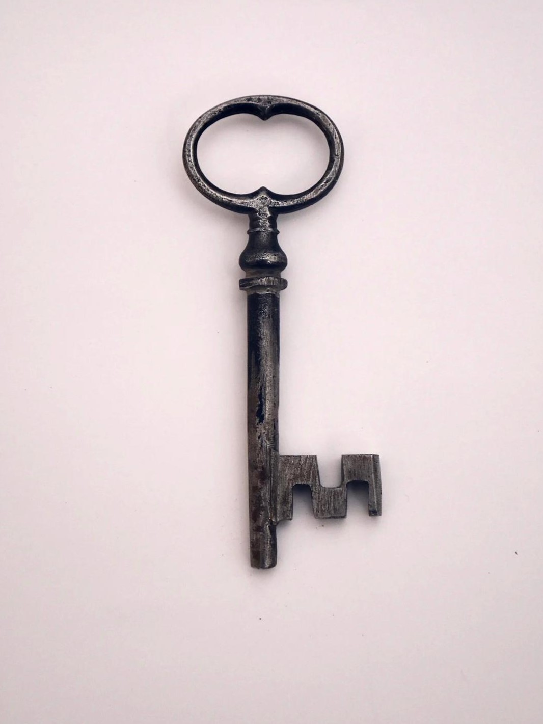 Vanha musta metallinen avain haalealla pohjalla