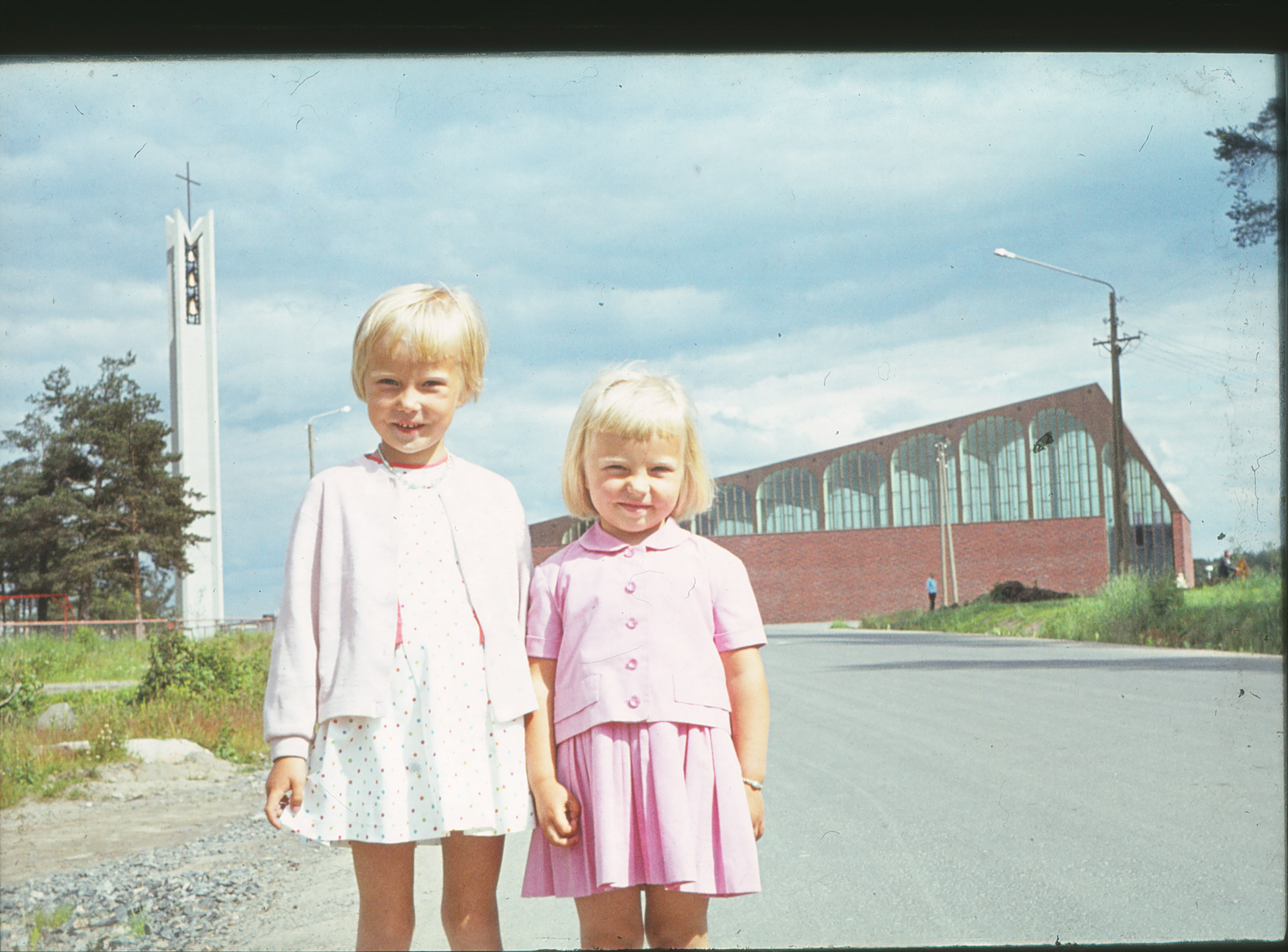 Kaksi lasta seisoo Karjasillan kirkon edessä 1960-luvulla otetussa kuvassa.