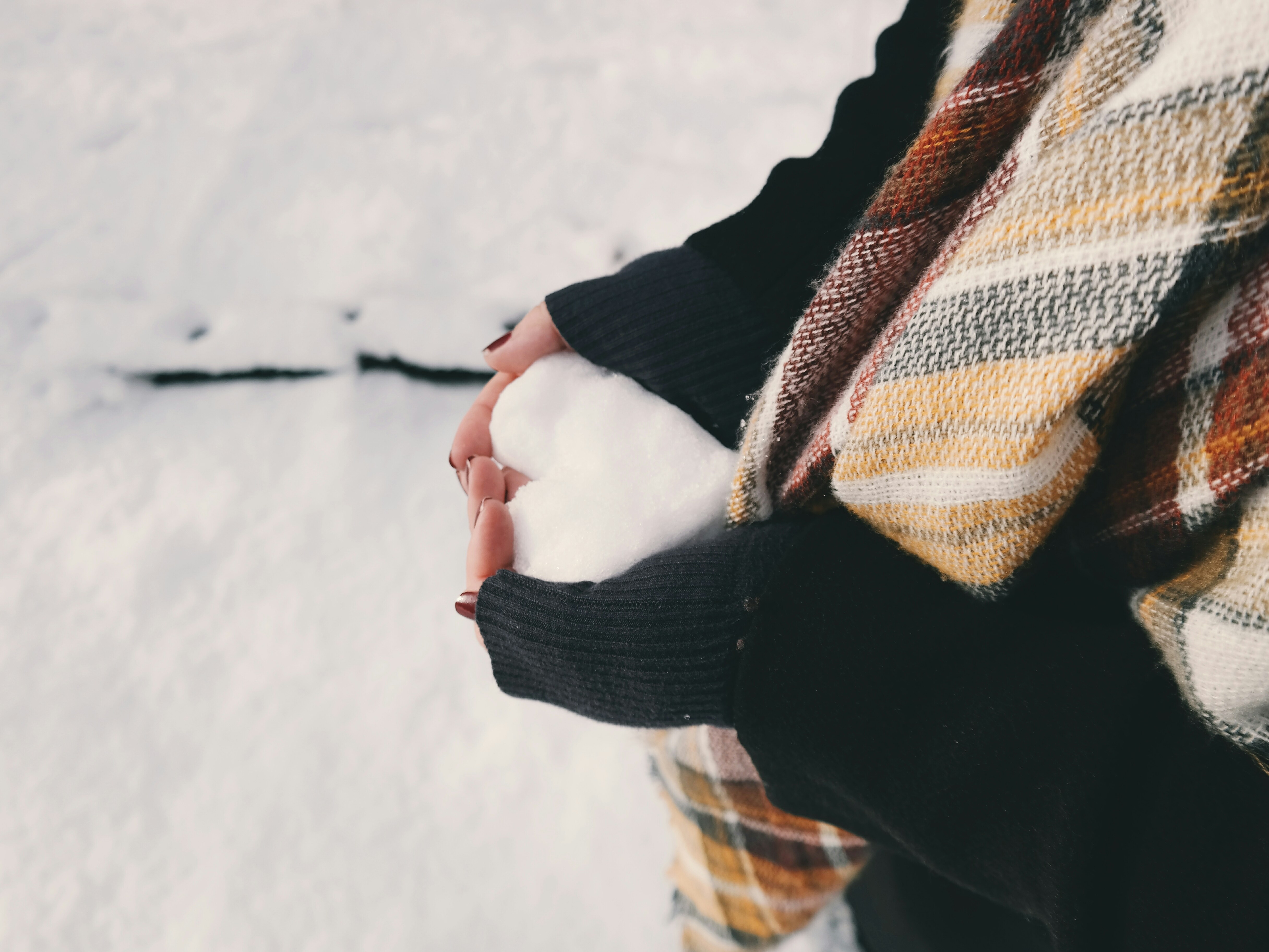 Tytön kädessä lumipallo, joka on tehty sydämen muotoiseksi. Kuva Brigitte Thom / Unsplash