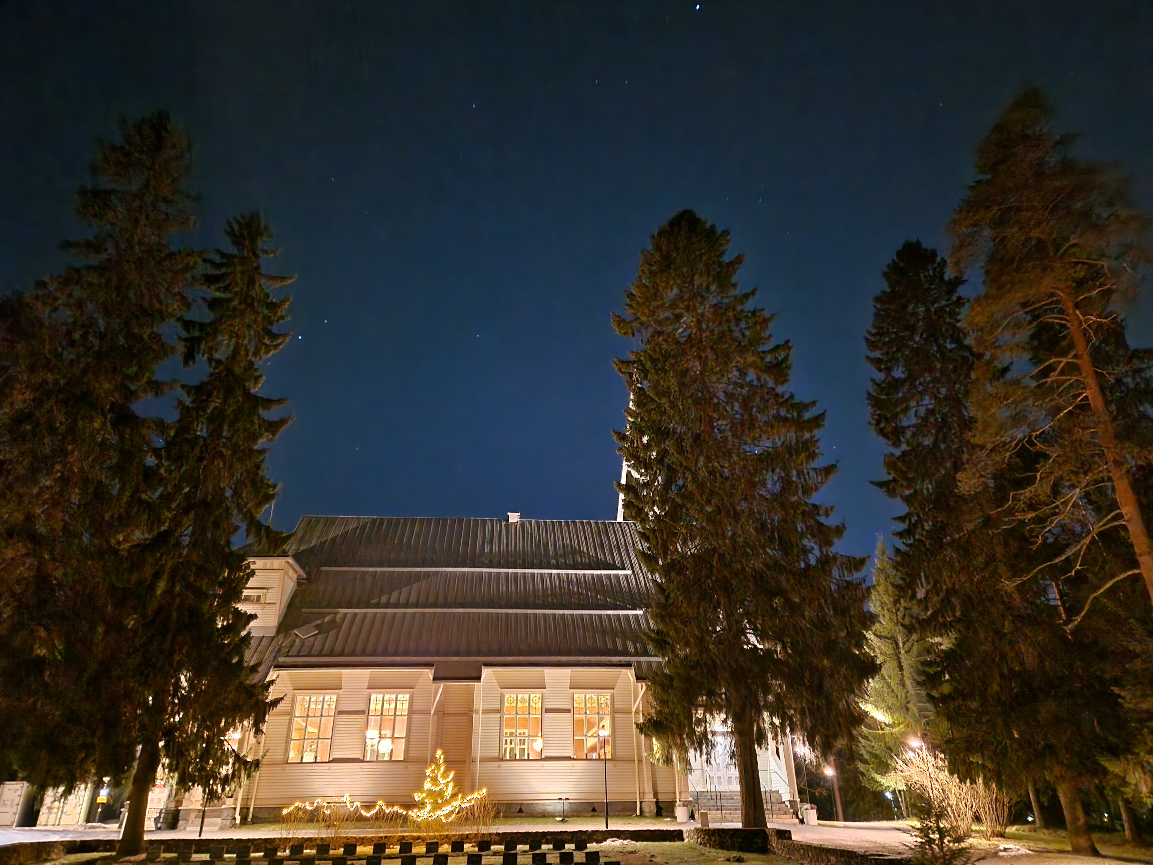 Valaistu Oulujoen kirkko pimeässä kuvattuna.