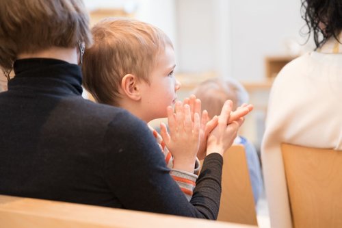 Lapsi istuu kirkossa äidin sylissä