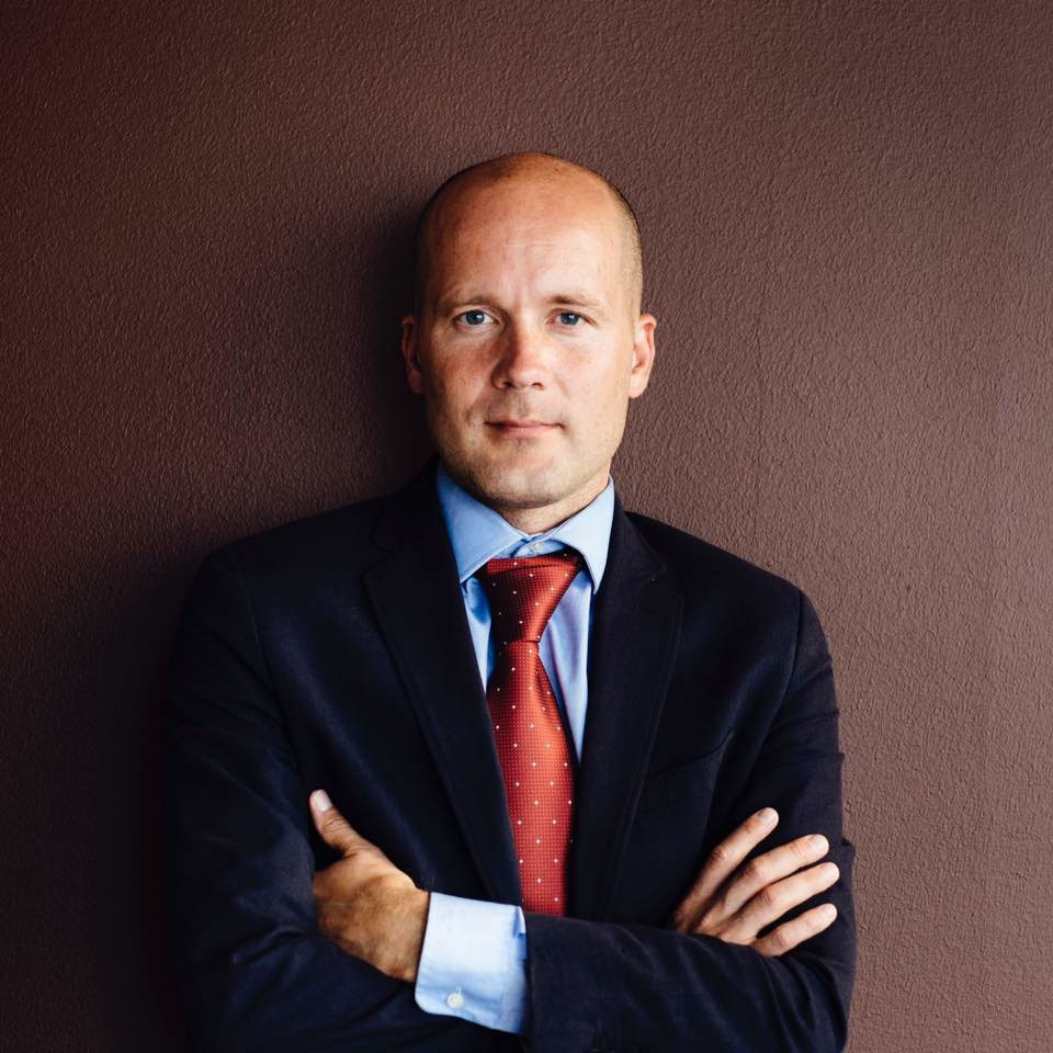 Kuva Antti Pentikäisestä yllään musta puku, punainen kravatti ja sininen kauluspaita.