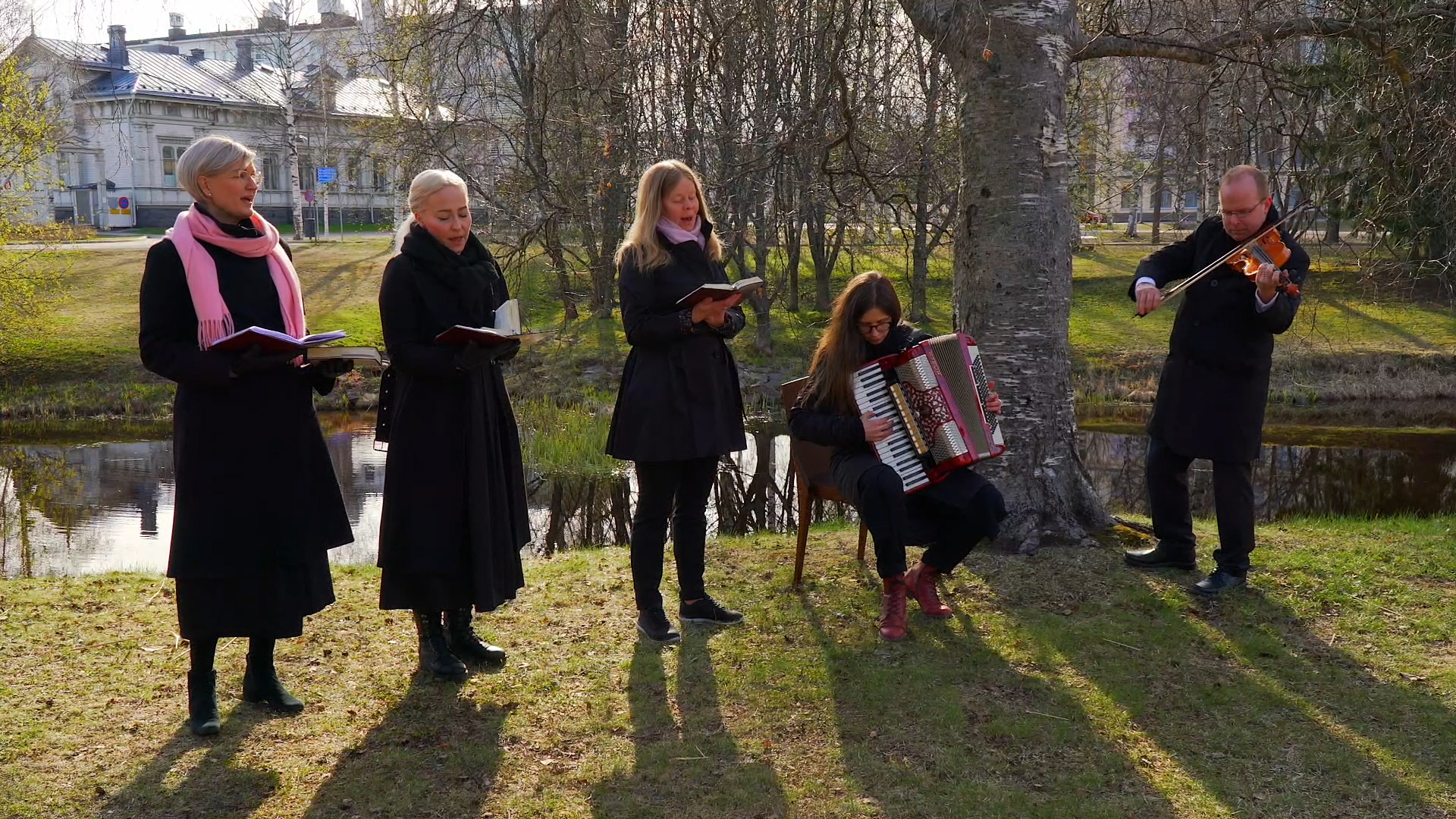 Oulun tuomiokirkon työntekijät laulavat keväisessä Ainolanpuistossa.