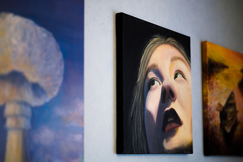 Kolme maalausta seinällä, joista reunimmaiset näkyvät vain osittain. Keskellä on maalaus, jossa on naisen k...