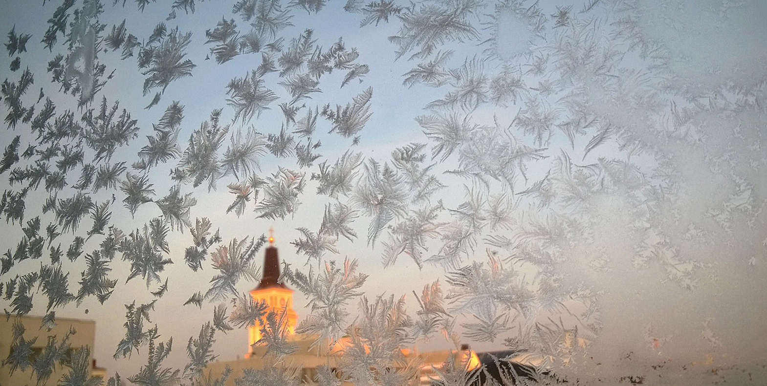 Oulun tuomiokirkkoseurakunnan risti kuvattuna pakkaspäivänä ikkunan läpi.Ikkunassa on kuurankukkia. Kuva: S...