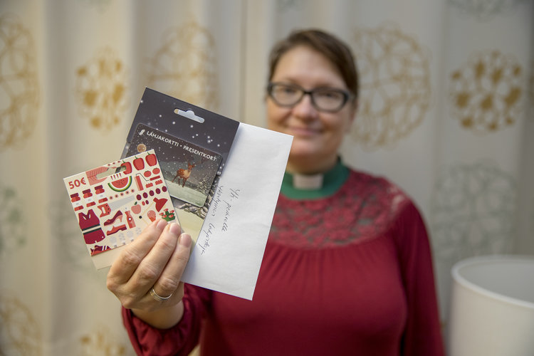 Kuvassa nainen, Oulun tuomiokirkkoseurakunnan diakoniatyöntekijä Heidi Karvonen. Kädessään hänellä on lahja...