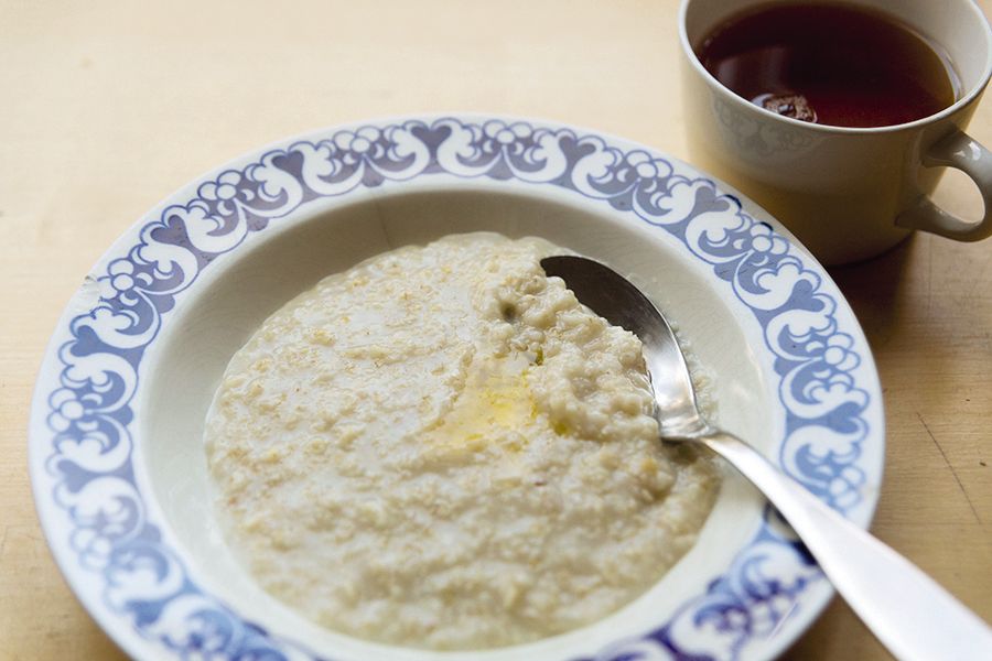 Kaurapuuroa voisilmällä sinivalkoisessa lautasessa. Lautasen vierellä maitolasi.