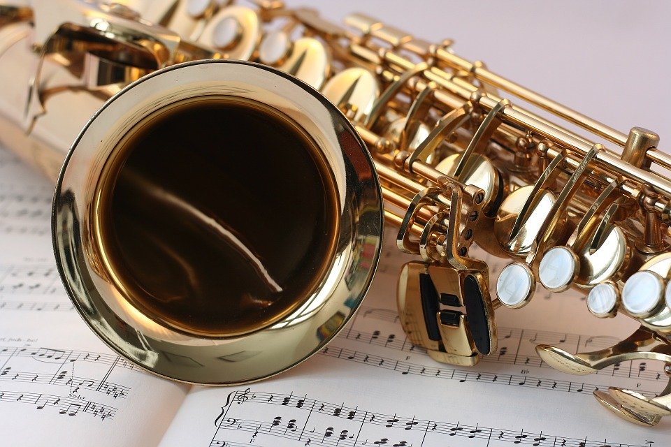 Kuvassa kullanvärinen saksofoni pöydällä nuottipaperin päällä