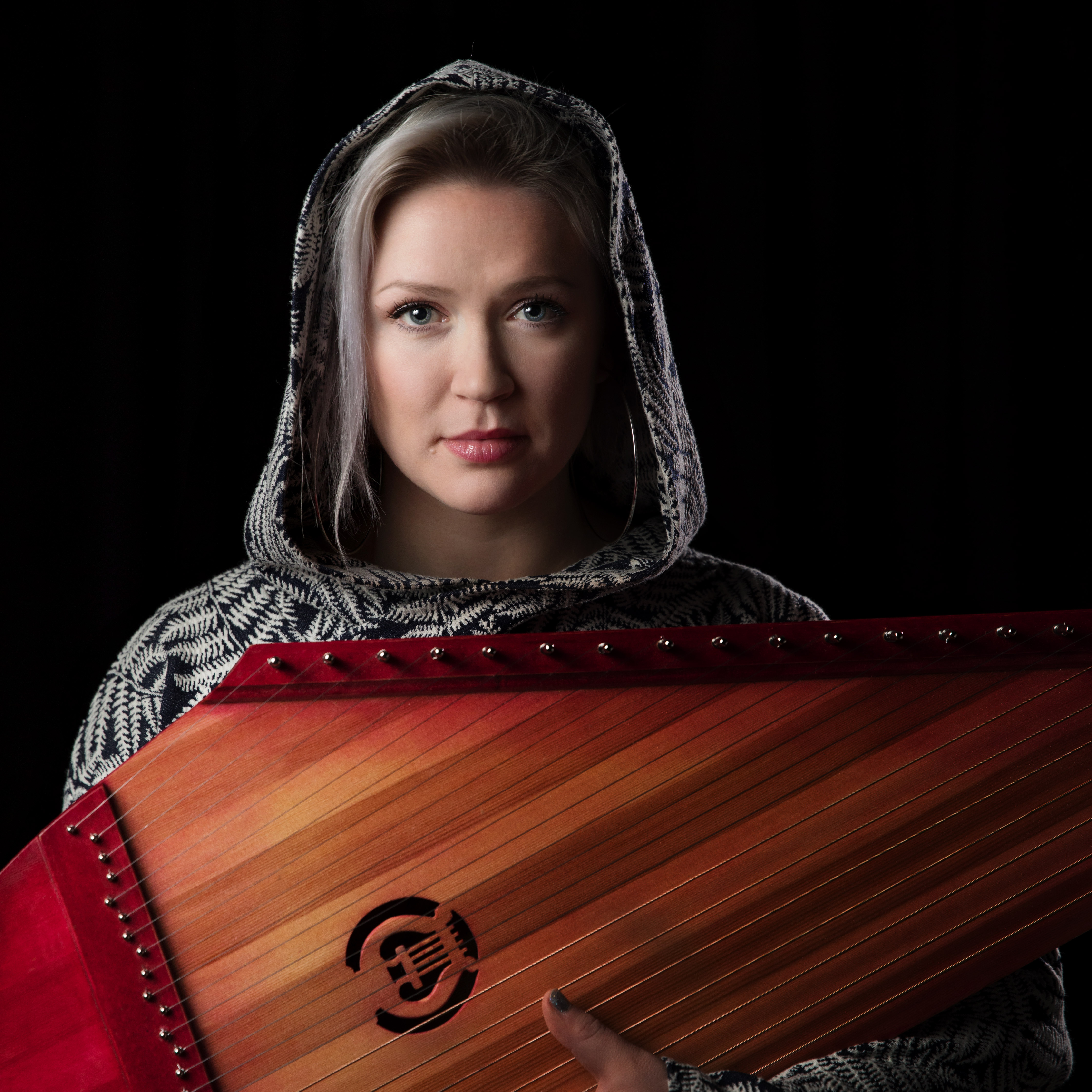 Taustatarinaklubi - artistina Maija Kauhanen Muusikko Maija Kauhanen huppu päässä ja kannel sylissä.