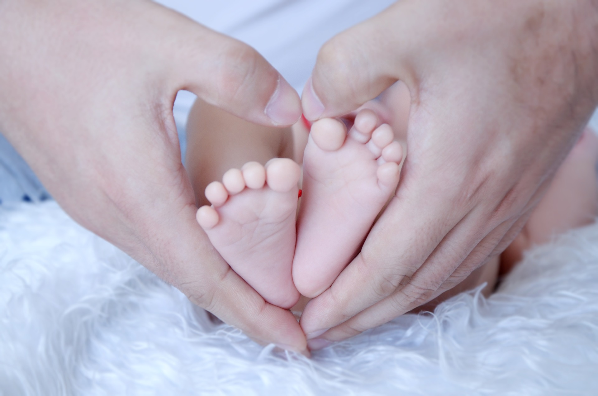 Kuvassa on vauvan jalat ja aikuisten kädet suojana.