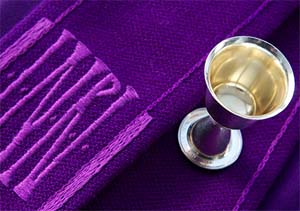 Ehtoollismalja violetin tekstiilin päällä, jossa lukee INRI.