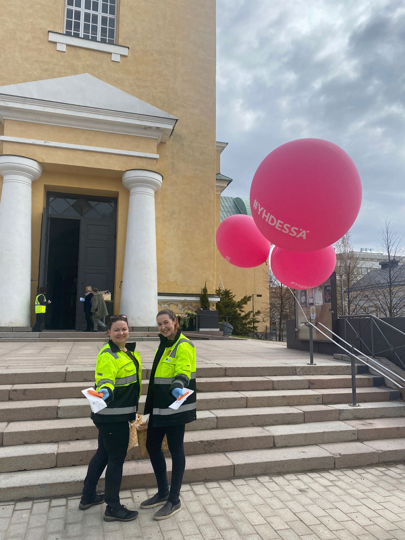 Kaksi hankkeen työntekijää Oulun tuomiokirkon portailla ojentamassa porkkanoita.